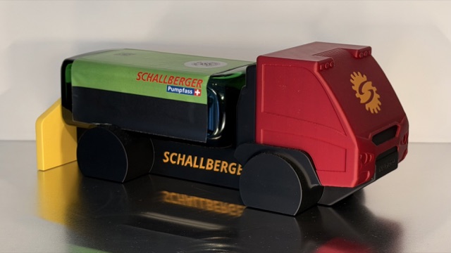 Seitliche Nahaufnahme eines farbigen 3D-gedruckten AEBI Transporters mit Jägermeister-Flasche und Schallberger-Branding