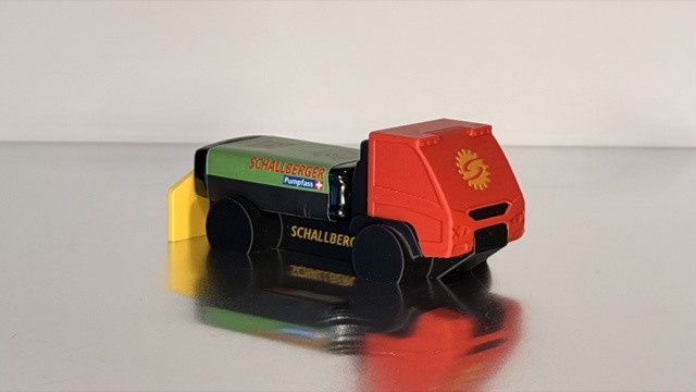 Gesamtansicht des AEBI Transporters mit roter Kabine, grünem Pumpfass und gelbem Anbauteil